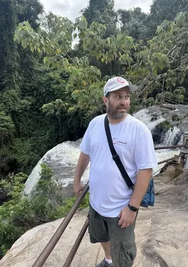 A guest at the base of a waterfall on a retreat excursion